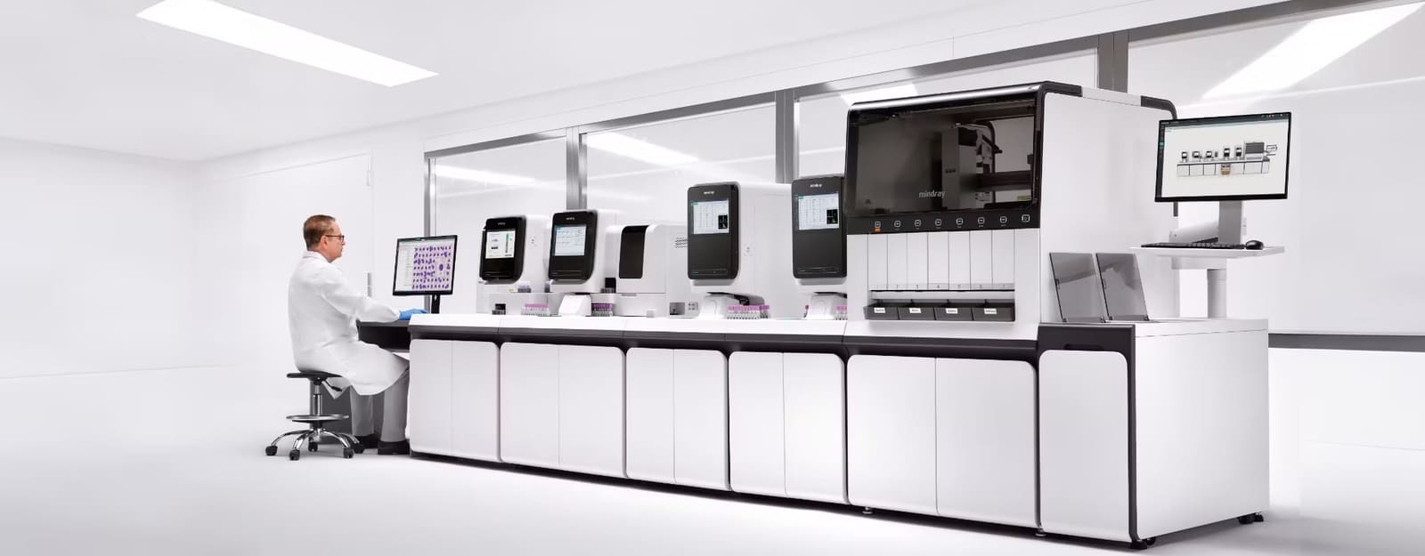 Mindray CAL 9000 cellular analysis line running the length of a laboratory bench, with a medical technologist reviewing blood-film images on screen